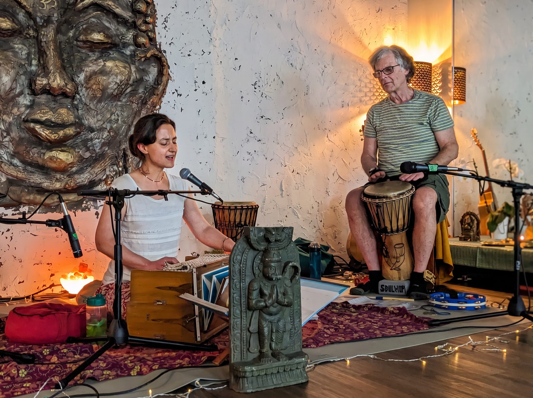 SOULHUM performing kirtan in front of a Buddha mural